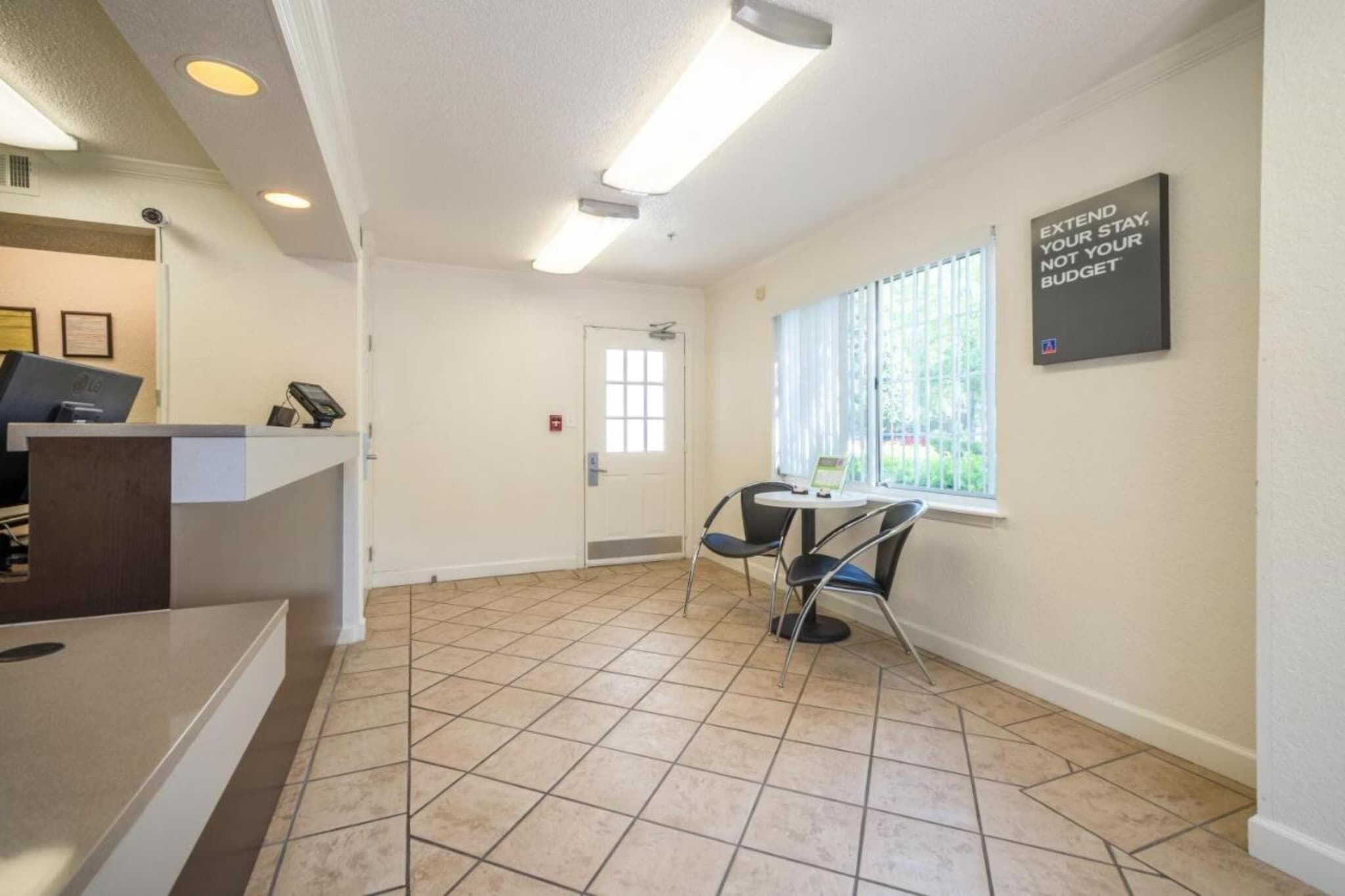 A reception area with a counter, a door, and a window with blinds.