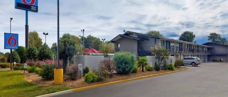 A motel with a clear entrance sign, a parking lot, and a building with a modern design.