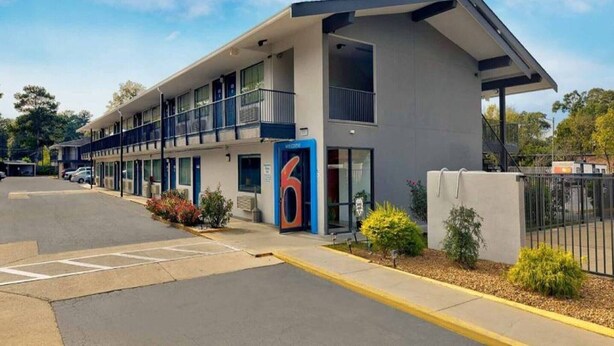 A motel with a large sign, multiple balconies, and a parking lot. - 2 FULL BEDS | Non-Smoking (Columbus GA)