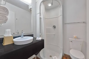 Un baño con lavamanos blanco, espejo y cabina de ducha.