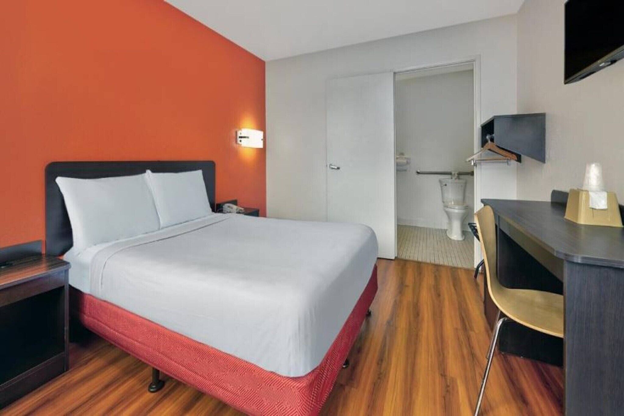 Ein Hotelzimmer mit Bett, Schreibtisch, Stuhl, Fernseher und Badezimmer.