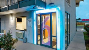 Moderni rakennus, jossa on pysäköintialueen opastekyltti, pyörätuolilla kulkemisen esteettömyyttä osoittava symboli ja numero 3050 julkisivussa.