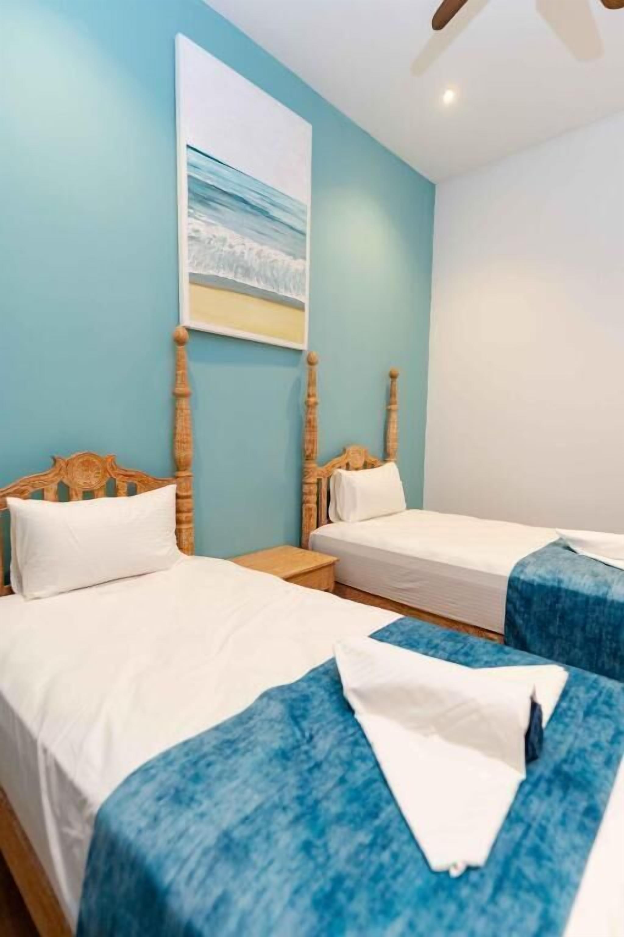 A hotel room with two beds, a large window, and a ceiling fan.