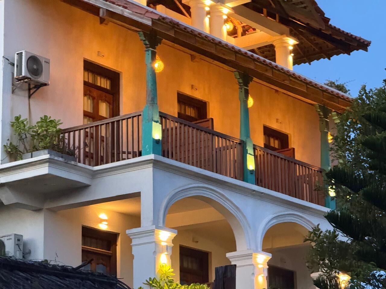 Un edificio de varios pisos con balcones, columnas y una serie de puertas.