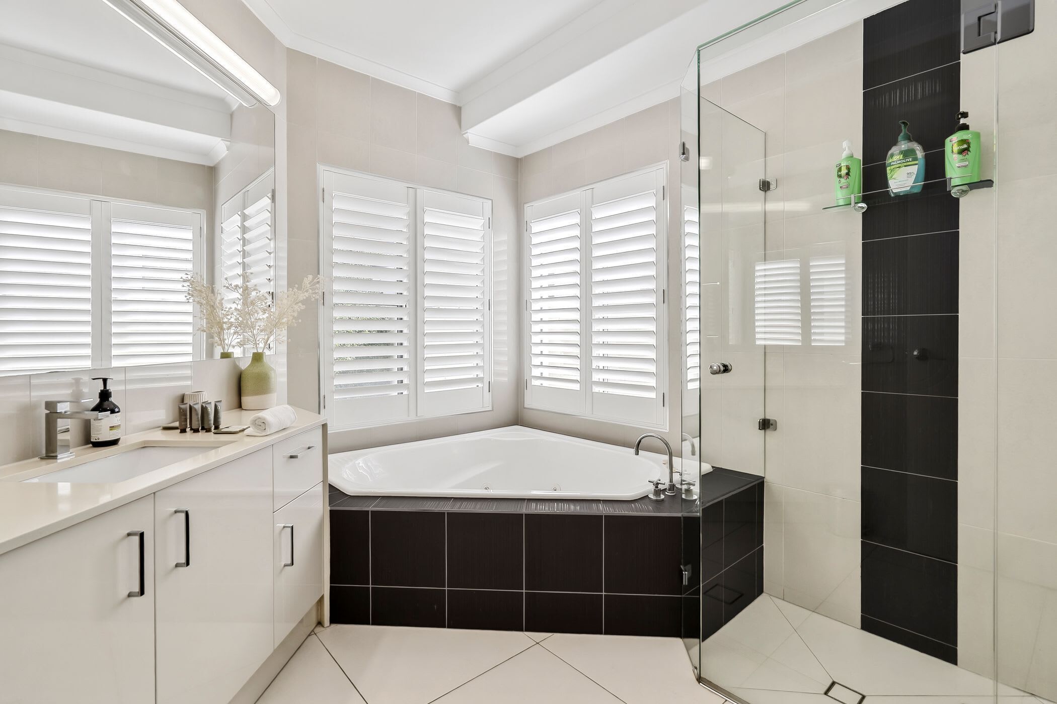 A modern bathroom with a large bathtub, a glass shower enclosure, and a vanity with a mirror.