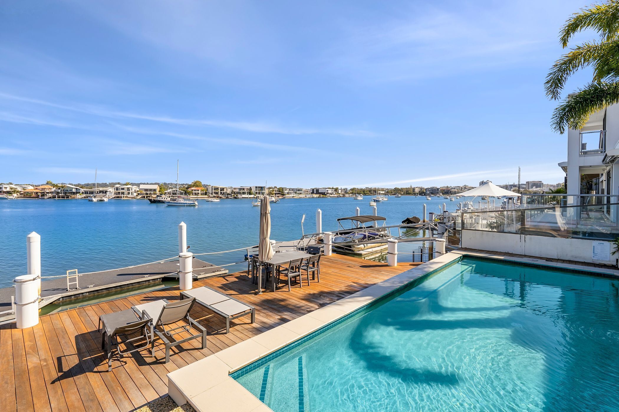 A pool area with lounge chairs and a view of the marina.