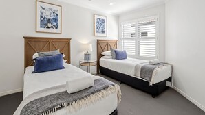 A bedroom with two beds, a ceiling fan, and a window with blinds. - Waterfront Oasis (Minyama)