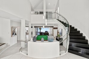 Ein modernes Interieur mit einer geschwungenen Treppe, einem Billardtisch und einer Glasreling.