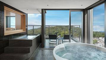A modern bathroom with a large bathtub, a wooden bench, and a view of the surrounding landscape.