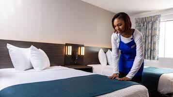 A hotel room with a bed, a nightstand, a lamp, and a window with curtains.
