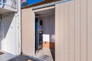 Une entrée d’immeuble avec une porte donnant sur une pièce où se trouve une machine à glaçons.