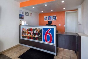 Un comptoir d’accueil doté d’un écran numérique, une porte et un sol carrelé.