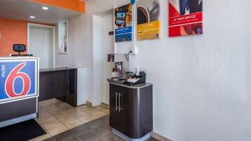 A hotel lobby with a reception desk, a kitchenette, and a small counter with a coffee machine.