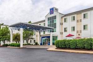 A hotel with a covered entrance, a prominent '6' sign, and a well-maintained garden. - 1 Full Bed | Mobility Access Tub, Nsmk (Caseyville)