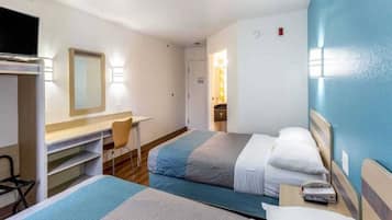 A hotel room with two beds, a desk, a chair, and a TV.