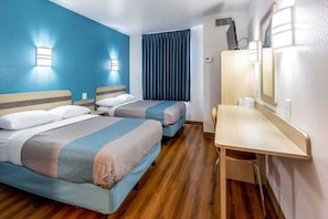 A hotel room with two beds, a desk, and a mirror.