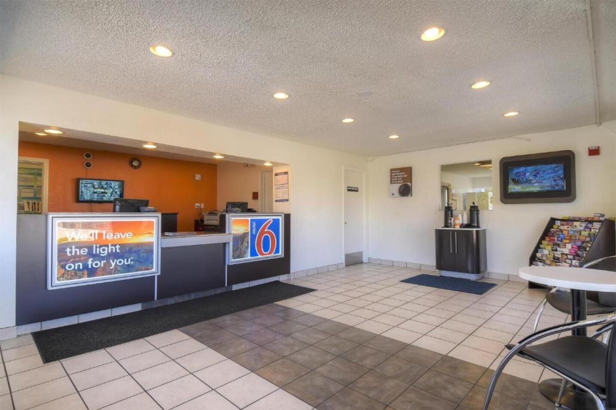 A reception area with a counter, a digital screen, and a coffee station.