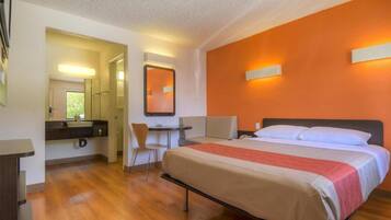 Una habitación de hotel con una cama, un escritorio y una silla.