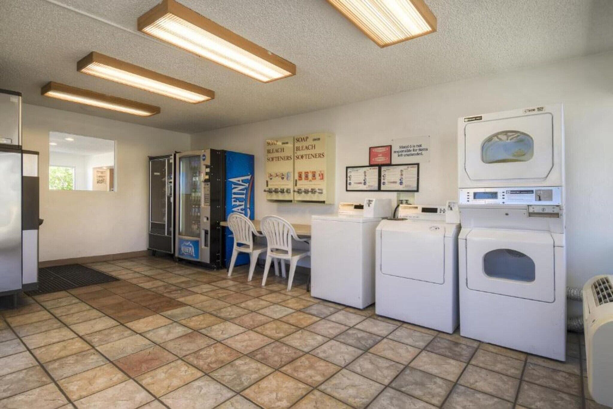Una sala de lavandería con lavadoras, secadoras y un quiosco de autoservicio.