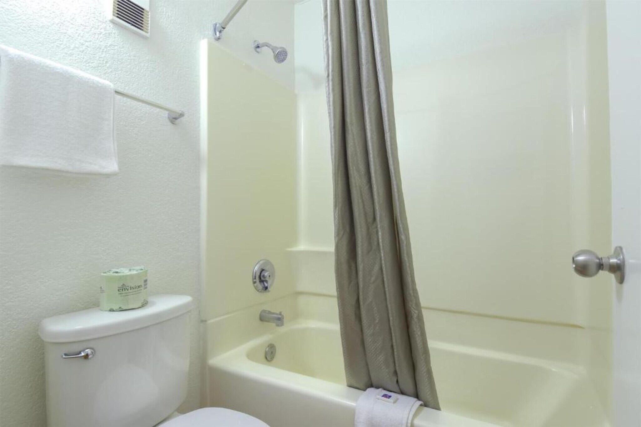 A bathroom with a toilet, a bathtub, and a shower curtain.
