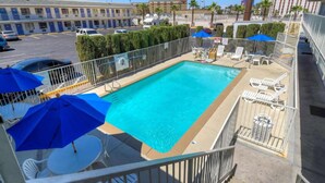 Piscina no terraço com vista para um parque de estacionamento e edifícios.
