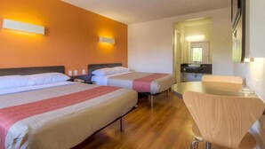 Quarto de hotel com duas camas, uma mesinha e uma cadeira.