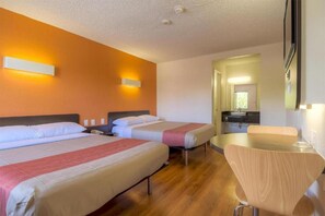 Una habitación de hotel con dos camas, una mesita pequeña y una silla.
