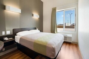 Une chambre d’hôtel avec un lit, une table de chevet et une fenêtre avec des rideaux.