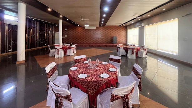 Un salón de conferencias con mesas redondas, sillas blancas y manteles rojos.