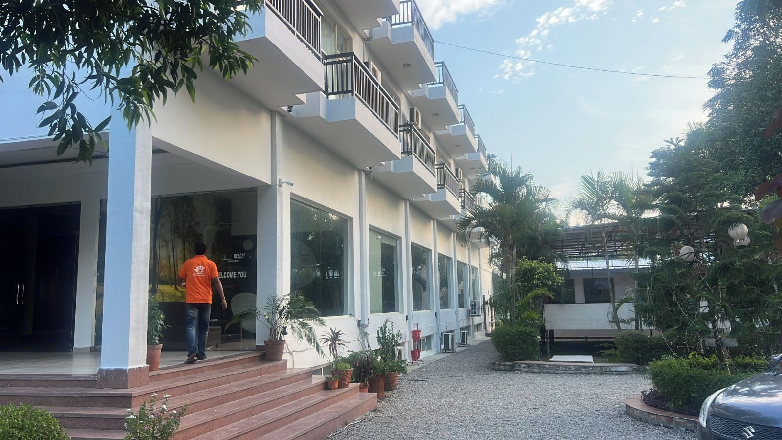 A building with a balcony, potted plants, and a gravel pathway.