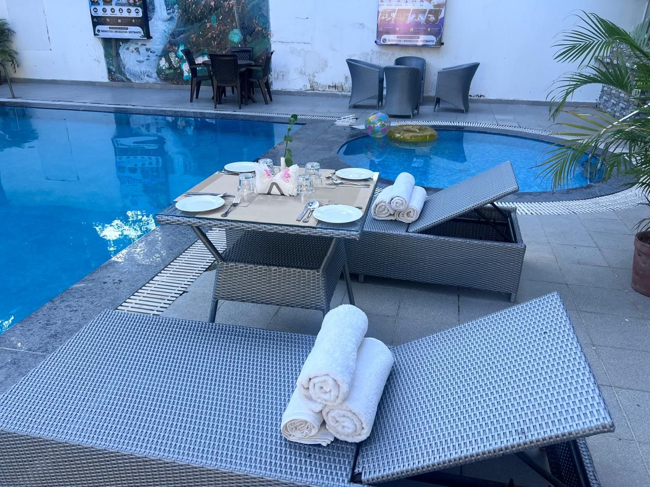 Un área junto a la piscina con sillones de descanso, una mesa dispuesta para comer y un globo decorativo.