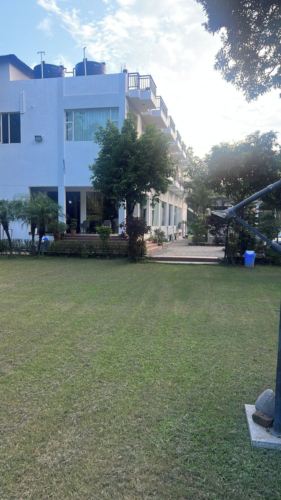 A grassy courtyard with a building featuring large windows and a balcony.