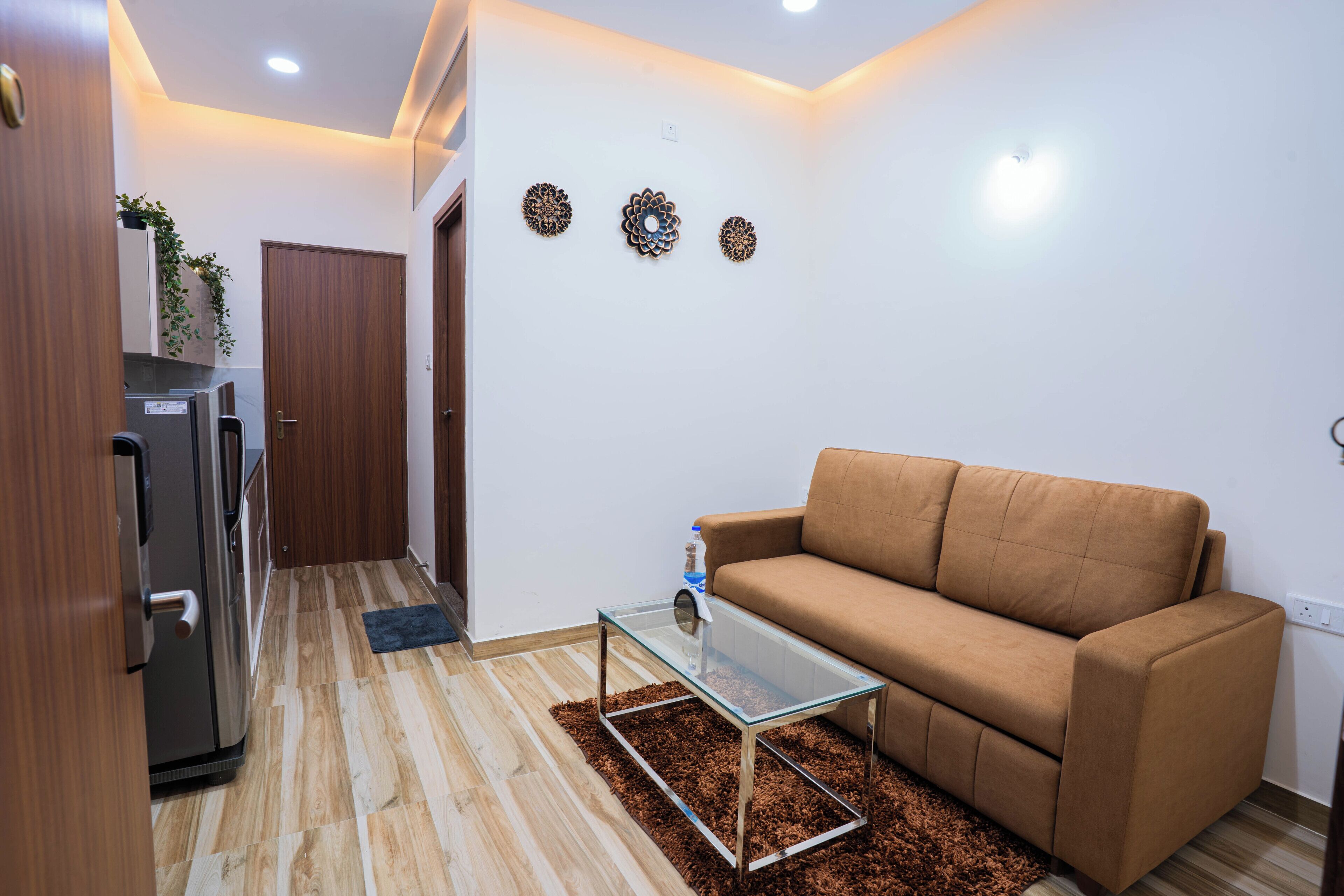 A living room with a brown sofa, a glass coffee table, and a wooden floor.