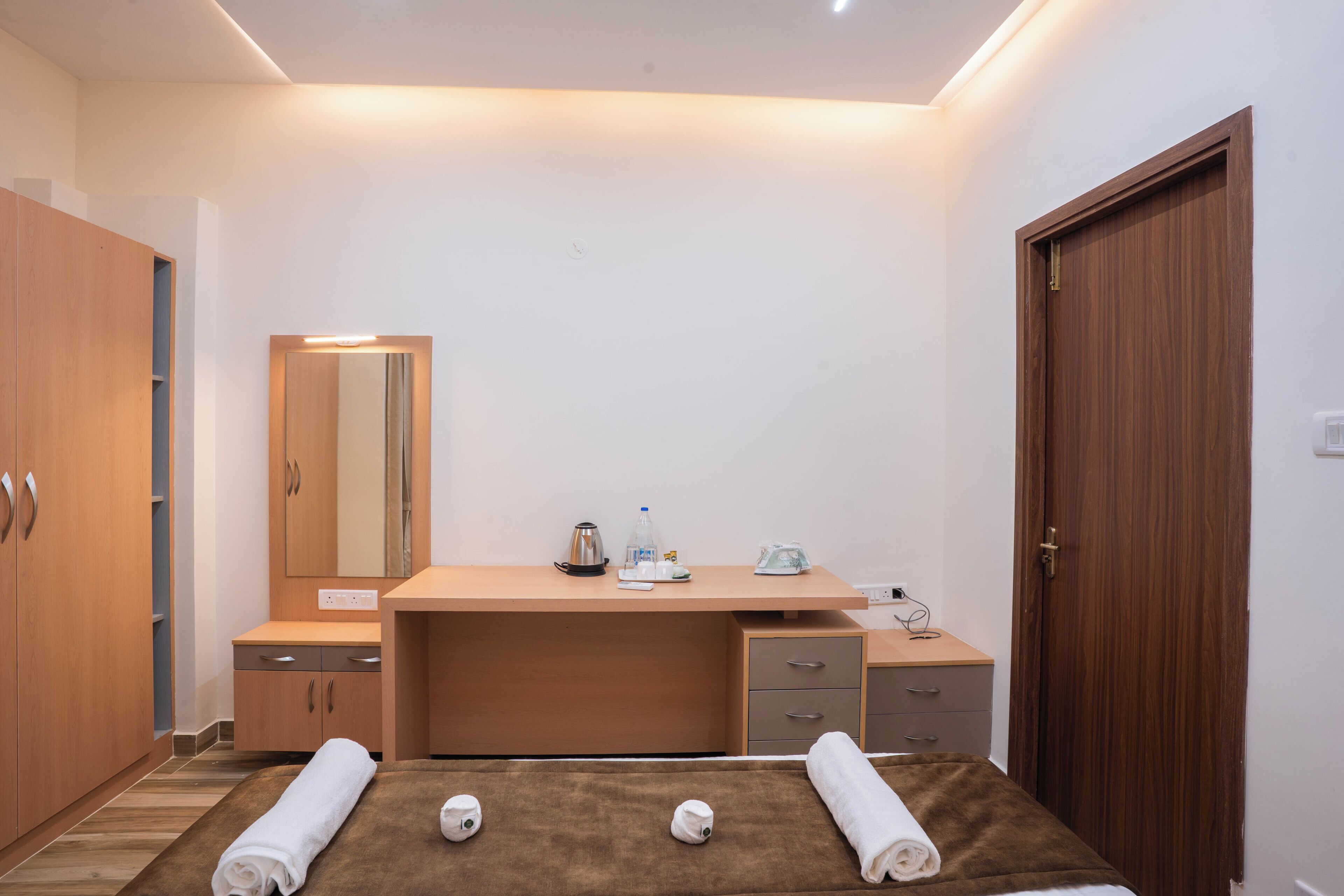 A modern bedroom with a wooden desk, a mirror, and a bed with towels.