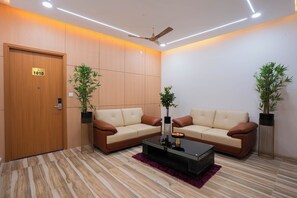 A modern waiting area with two sofas, a coffee table, and potted plants. - Sri Utham Suites (Bengaluru)