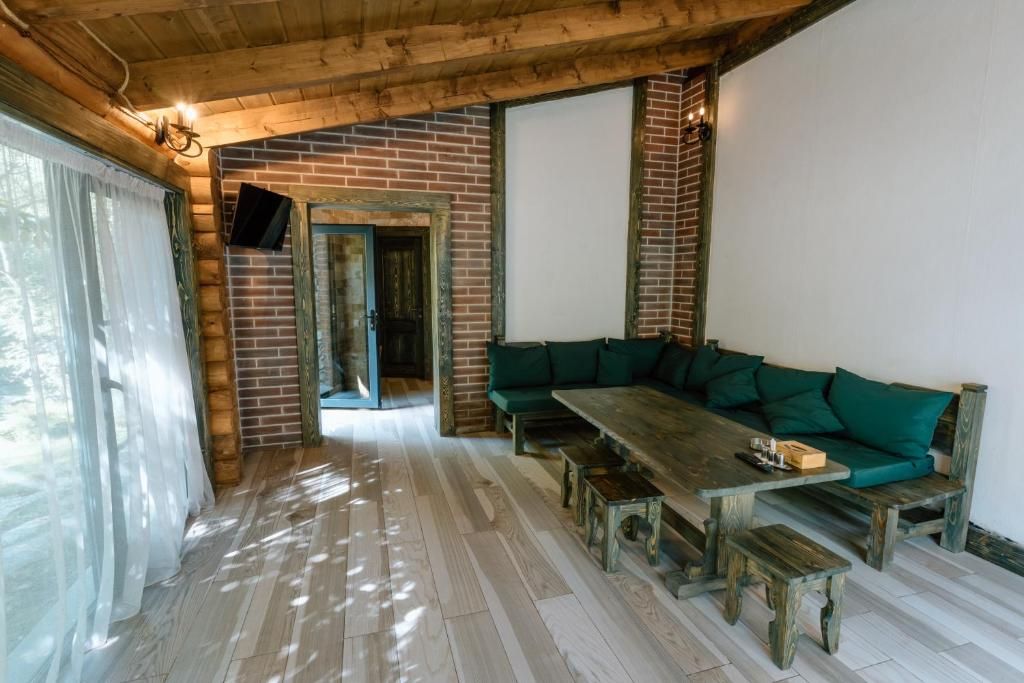 Ein Holzinnenraum mit einer Ziegelwand, einem grünen Sofa und einem Holztisch mit Bänken.