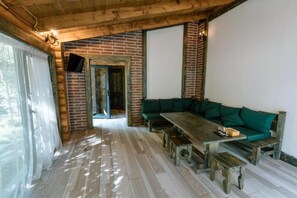 Un interior de madera con una pared de ladrillo, un sofá verde y una mesa de madera con bancos.
