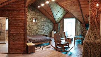 Un dormitorio rústico con pared de piedra, techo de madera y una cama grande.