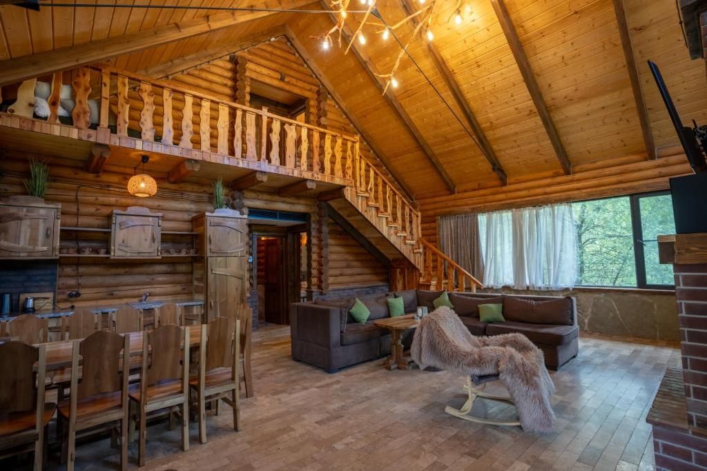 A log cabin interior with a dining area, a sofa, and a staircase.