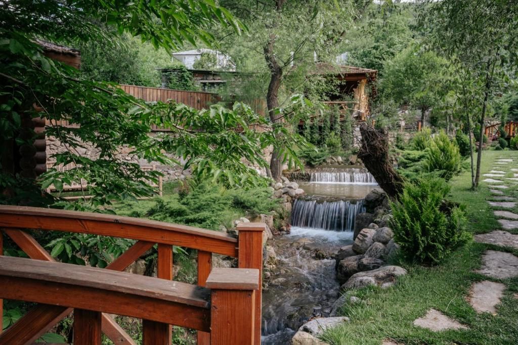 Un puente de madera sobre una cascada pequeña en un jardín exuberante.