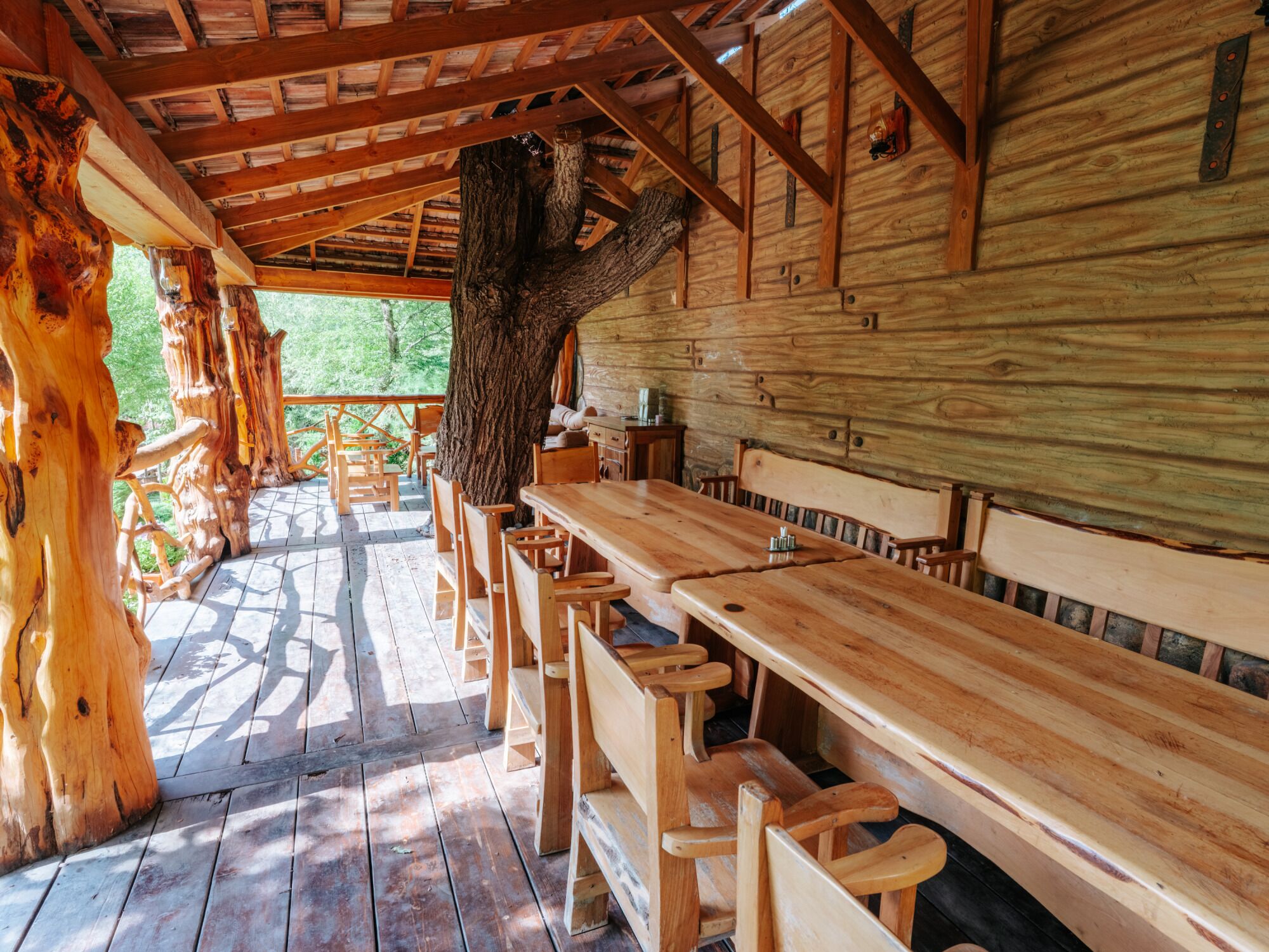 A wooden cabin with a dining area featuring benches and a table.