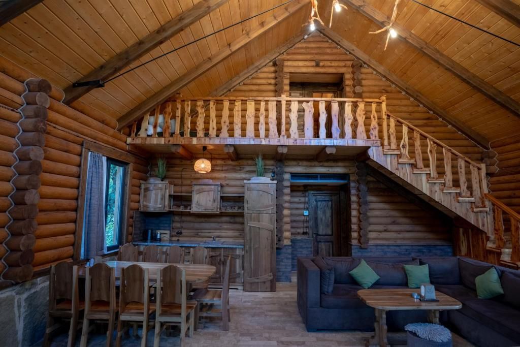 A log cabin interior with a dining area, a sofa, and a staircase.