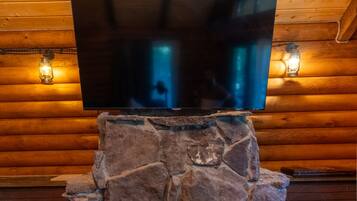 Un televisor de pantalla plana montado en una chimenea de piedra en una cabaña de troncos.