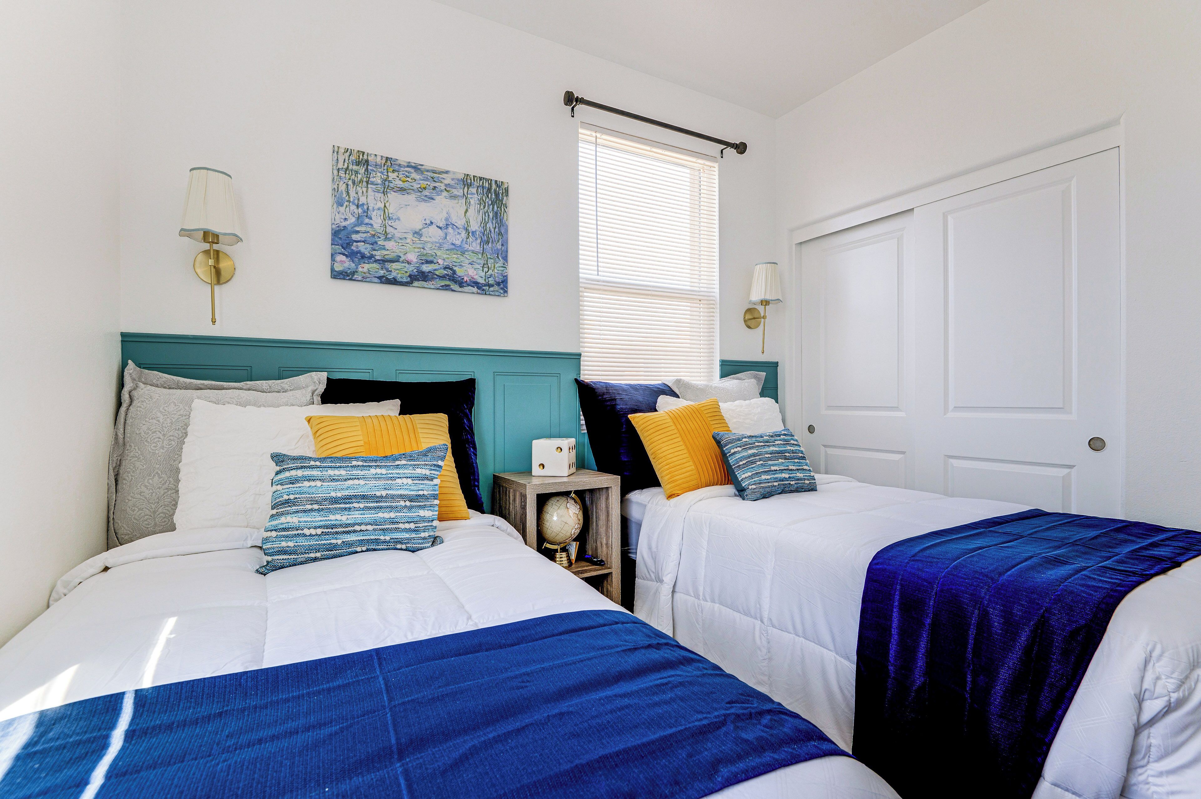 Une chambre à coucher avec deux lits, chacun recouvert d’une couvre-lit bleue et blanche, et un globe posé sur une table de chevet.