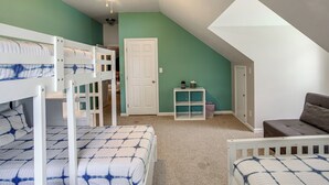 A room with bunk beds, a ceiling fan, a door, a small table, and a couch. - Pool, Dock & Sunset Views! Lake Wateree Retreat (Ridgeway)