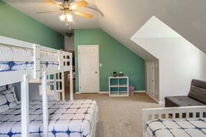 Ein Zimmer mit Stockbetten, Deckenventilator, Tür, kleinem Tisch und einer Couch.