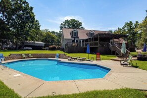 Ein Wohngrundstück mit Swimmingpool, Holzdeck und überdachter Terrasse.