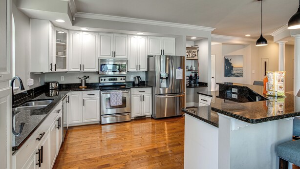 A modern kitchen with white cabinetry, stainless steel appliances, and a wooden floor. - Pool, Dock & Sunset Views! Lake Wateree Retreat (Ridgeway)