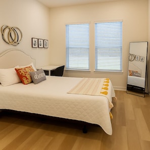 Une chambre bien rangée, avec un lit, des tables de chevet, une chaise et un miroir.