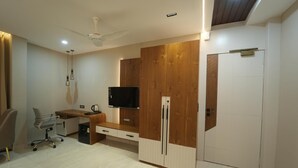 Una habitación moderna con escritorio, silla, televisor, armario y ventilador de techo.